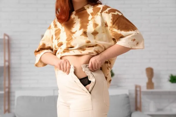 Image of woman trying to do her trousers up after pregnancy weight gain Seacombe